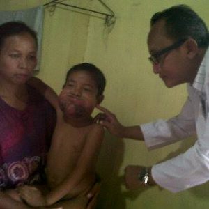 Penderita tumor asal Blangkejeren dipangku orangtuanya dan didampingi dr. Witono.(LGco-Istimewa)
