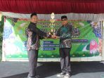 Kepsek SMPIT Raudhatul Jannah Ujang Hamka, S.Pd (kiri) menyerahkan piala kepada Juara Umum MIN 1 Blangkejeren (ist)